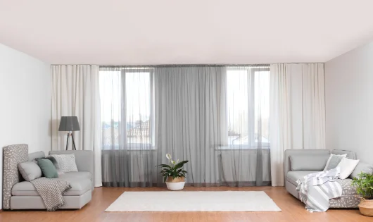 A living room with drapes and white furniture.