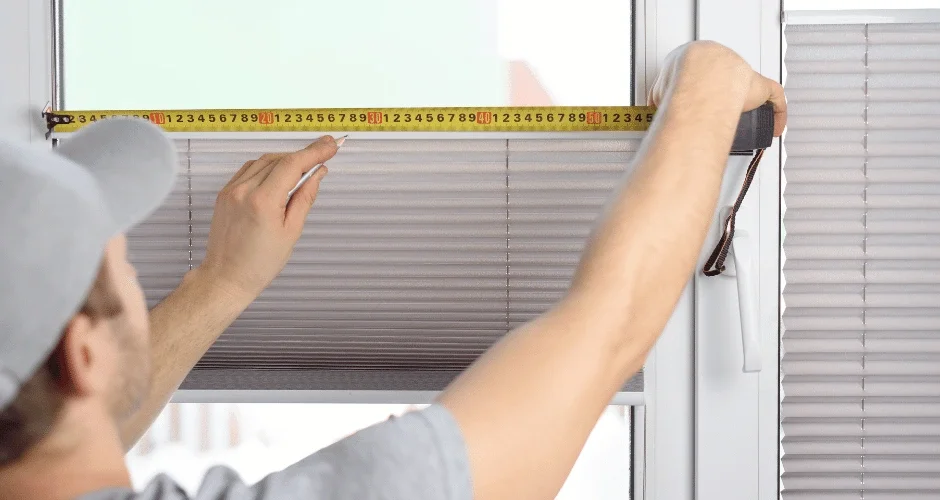 A man measuring window blinds with a tape measure
