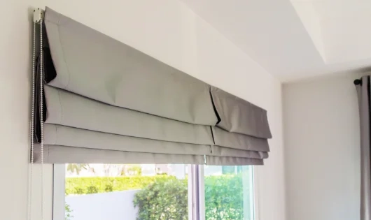 A window with a gray Roman shades