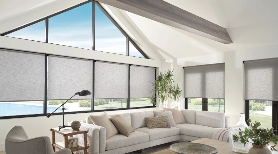 A living room with large windows and gray roller shades