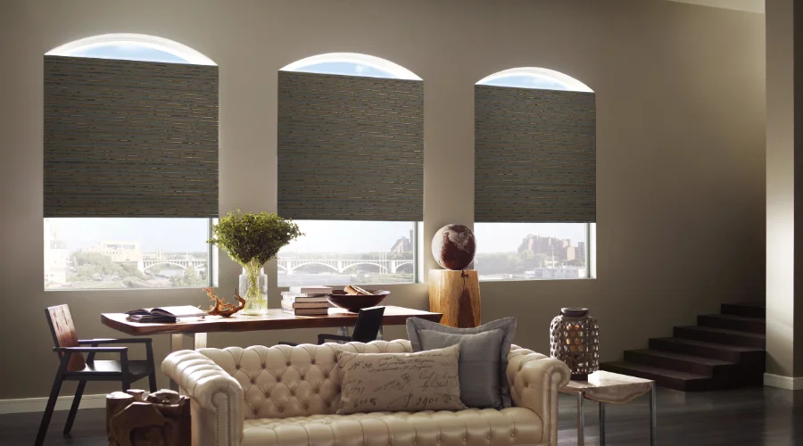 A living room with two large windows and a leather couch.