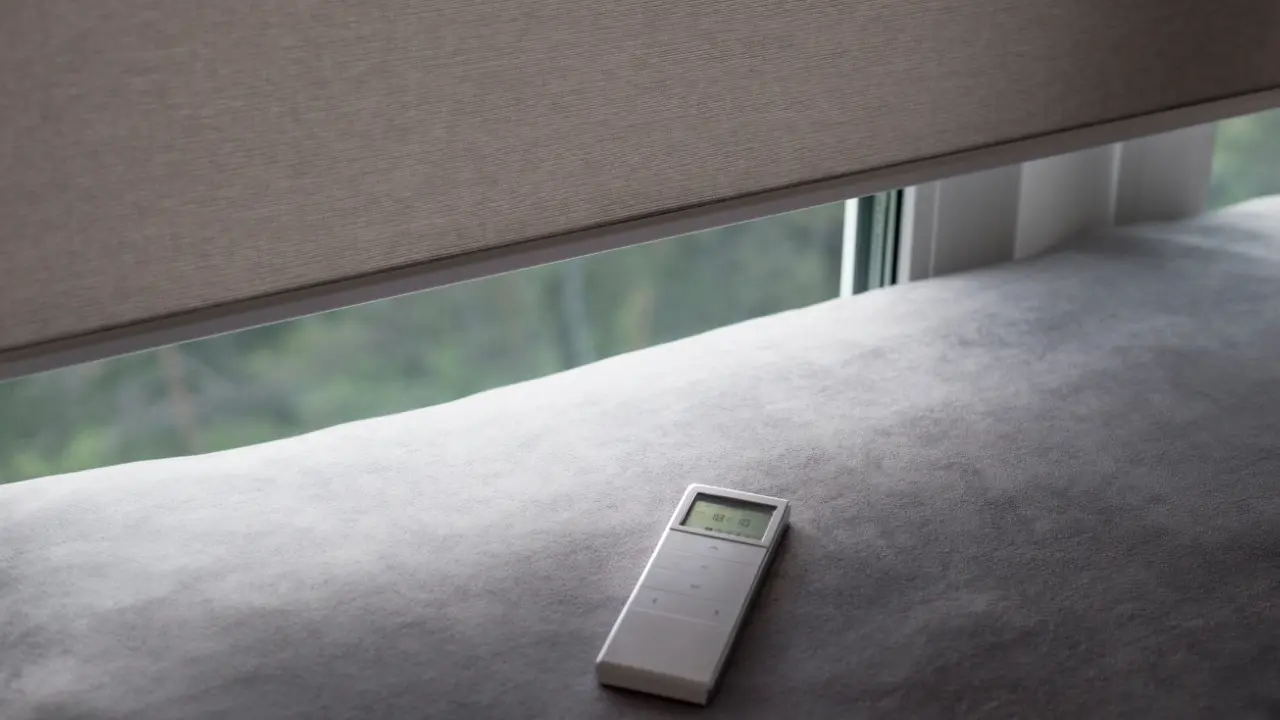 A remote control sits on a couch next to a window